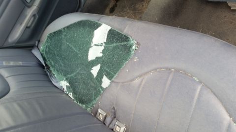 1991 Ford LTD Crown Victoria - The interior of a vehicle shows a damaged side window with glass fragments on the seat.