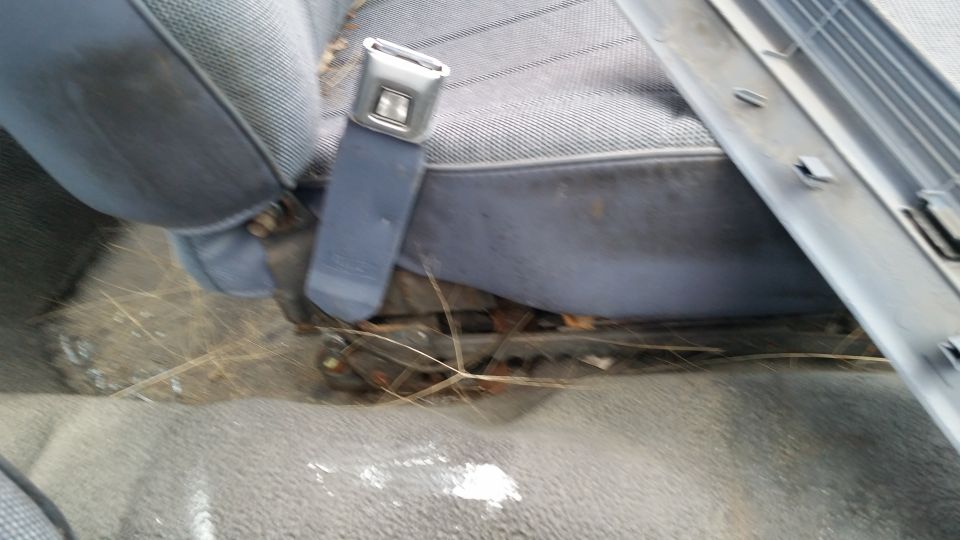 Close-up of a car's interior showing a blue fabric seat and a gray seatbelt buckle