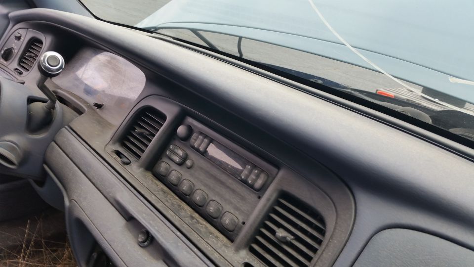 Dashboard of a dusty car interior showing a radio, vents, and gear shifter