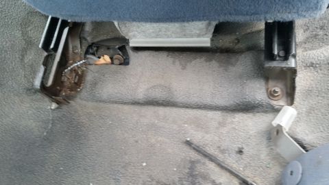 1991 Ford LTD Crown Victoria - Close-up view of the seat mounting hardware inside a vehicle.