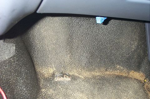 2001 Ford Crown Victoria - Close-up view of the textured floor and a blue electrical connector inside a vehicle's interior.