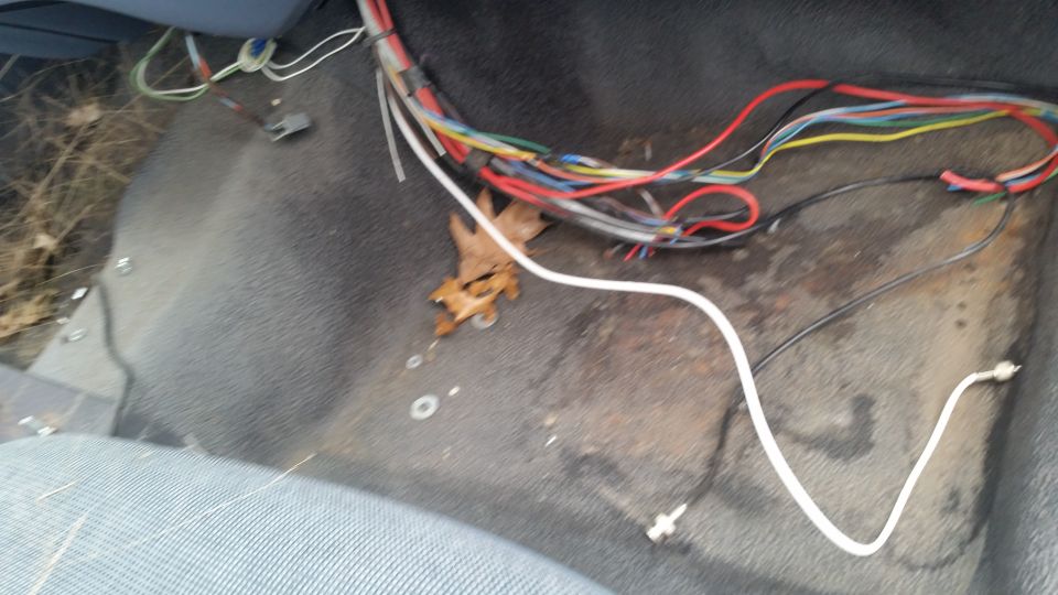Messy wiring harness and debris on the floor of a vehicle interior