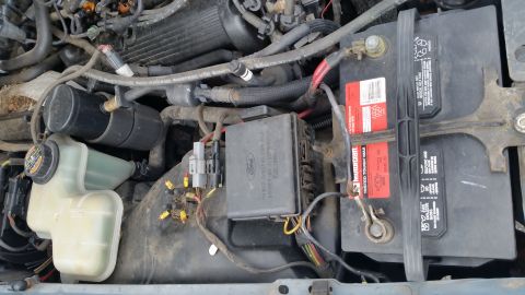 1991 Ford LTD Crown Victoria - Close-up view of a vehicle's engine bay, the battery, fuse box, and coolant reservoir.