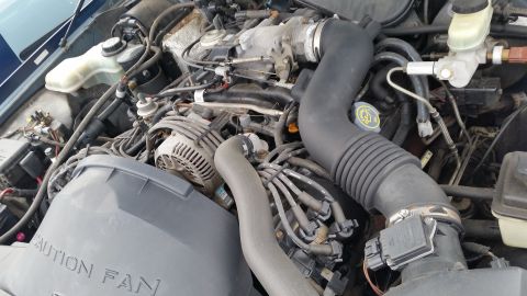 1991 Ford LTD Crown Victoria - Close-up of a vehicle's engine bay, showing various components and a caution fan cover.