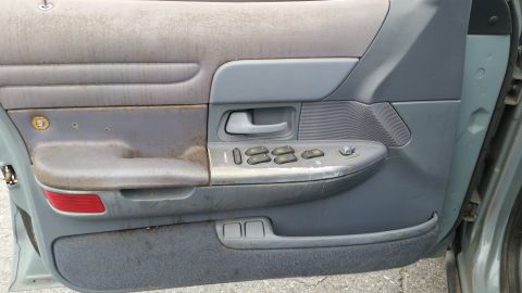 1991 Ford LTD Crown Victoria - Interior of a car door, showing worn fabric and plastic components, including window controls.