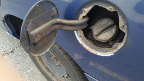 1991 Ford LTD Crown Victoria - Close-up of an open fuel door on a blue car, revealing the gas cap and surrounding area.