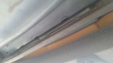 1991 Ford LTD Crown Victoria - Close-up view of the underside of a vehicle, revealing structural components and orange foam insulation.