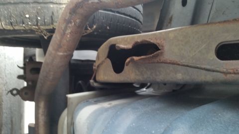 1991 Ford LTD Crown Victoria - Close-up of a heavily rusted vehicle frame showing significant corrosion and a hole.