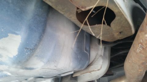 1991 Ford LTD Crown Victoria - Underside view of a vehicle's fuel tank and exhaust system, with debris caught on suspension components.