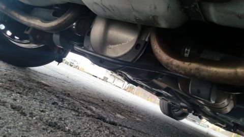 1991 Ford LTD Crown Victoria - The undercarriage of a vehicle is shown, focusing on the rear differential and exhaust system.