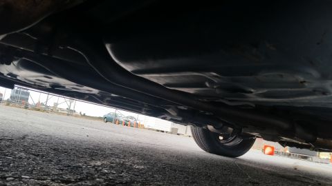 1991 Ford LTD Crown Victoria - The underside of a car is visible, with other vehicles parked in the background.