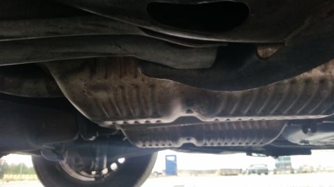 1991 Ford LTD Crown Victoria - A low-angle shot reveals the underside of a vehicle, focusing on the exhaust system and suspension parts.
