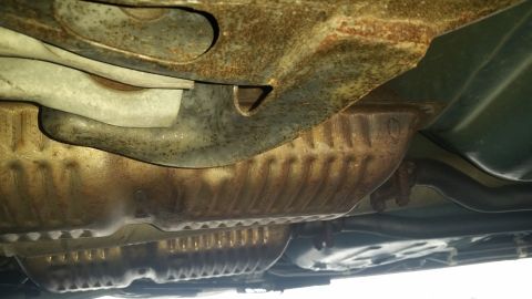 1991 Ford LTD Crown Victoria - The underside of a vehicle reveals significant rust on the exhaust system and frame components.