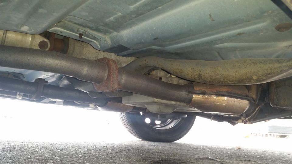 Underside of a car showing exhaust system and a wheel