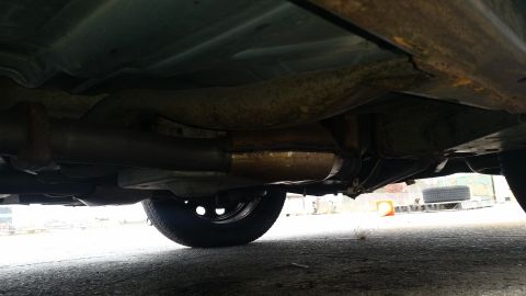 1991 Ford LTD Crown Victoria - The undercarriage of a vehicle displays significant rust and wear on its exhaust components.