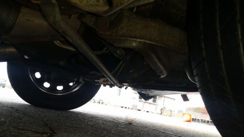 1991 Ford LTD Crown Victoria - A low-angle shot reveals the undercarriage of a vehicle, with a tire and suspension components visible.