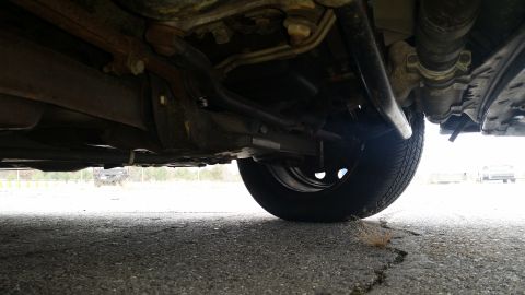 1991 Ford LTD Crown Victoria - A low-angle shot reveals the undercarriage and a tire of a vehicle, with no visible year-identifying features.