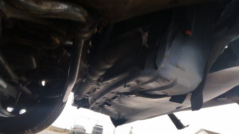 1991 Ford LTD Crown Victoria - A low-angle shot reveals the undercarriage of a vehicle, with various mechanical parts visible.