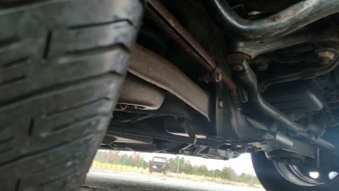 1991 Ford LTD Crown Victoria - Undercarriage view of a vehicle, with a tire prominent in the foreground and a truck visible in the distance.