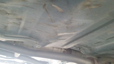 1991 Ford LTD Crown Victoria - The underside of a car is visible, showing exhaust pipes and a light blue undercarriage.