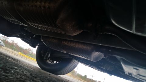 1991 Ford LTD Crown Victoria - The undercarriage of a vehicle is visible, including the exhaust system and a tire.