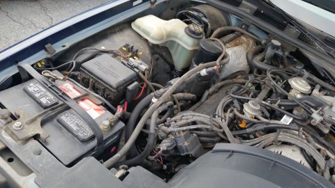 1991 Ford LTD Crown Victoria - The engine bay of a vehicle, showing the battery, fuse box, and various engine components.