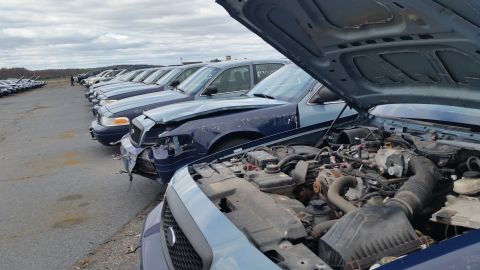 1991 Ford LTD Crown Victoria - Several police cruisers are parked in an outdoor lot, with one in the foreground showing its engine compartment.