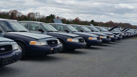 1991 Ford LTD Crown Victoria - A row of 1991 Ford Crown Victoria LTD sedans are parked in an outdoor lot under a cloudy sky.