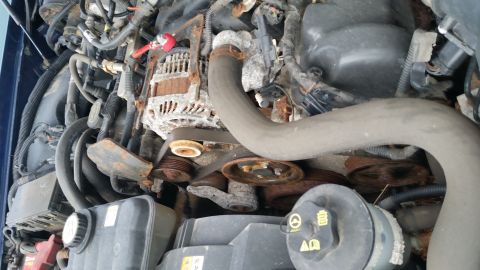 1991 Ford LTD Crown Victoria - Close-up view of a vehicle's engine bay, showing a rusty alternator and various pulleys and hoses.