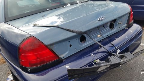 1991 Ford LTD Crown Victoria - The rear of a Ford Crown Victoria shows damage and missing parts, including the trunk lid and bumper assembly.