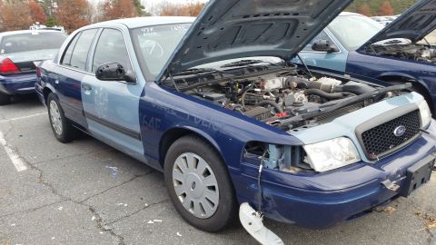 1991 Ford LTD Crown Victoria - Two Ford Crown Victoria police cars are parked with their hoods open, showing their engines.