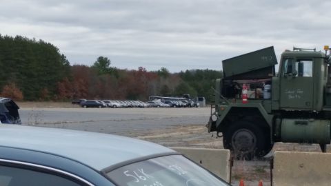 1991 Ford LTD Crown Victoria - A military truck sits in a lot with many cars parked in the distance under a cloudy sky.