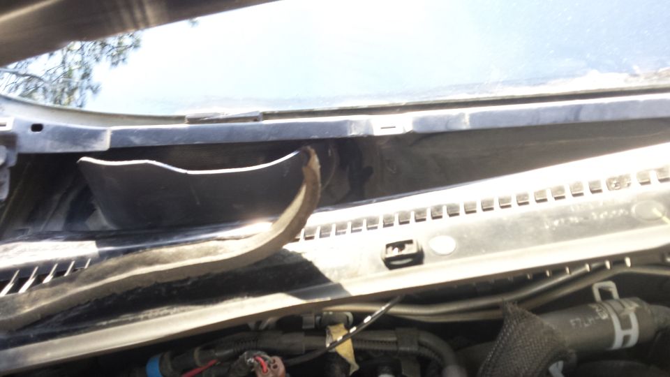 Underside of windshield cowl with some plastic trim detached and visible wiring