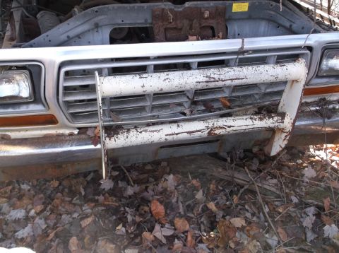 1974 Dodge Challenger - The front grille and bumper of a weathered pickup truck are visible, covered in rust and debris.