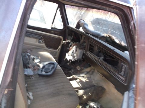 1974 Dodge Challenger - The interior of a brown truck shows significant damage to the dashboard and seats, with debris scattered throughout the cabin.