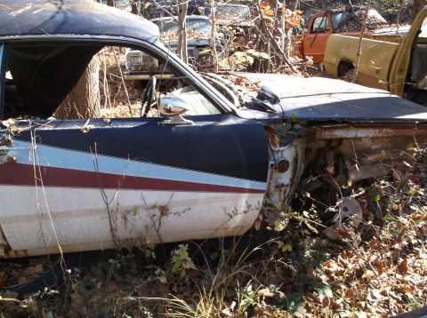 1974 Dodge Challenger - Abandoned 1974 Dodge Challenger sits in a junkyard with other vehicles.