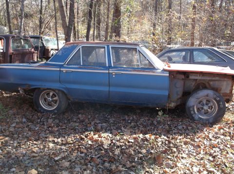 1974 Dodge Challenger - This blue sedan, likely a 1966 model, sits in a junkyard with its front end removed.