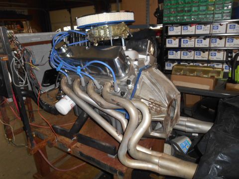1972 Ford Bronco - A V8 engine with chrome valve covers and exhaust headers is displayed on a workbench, ready for installation or restoration.