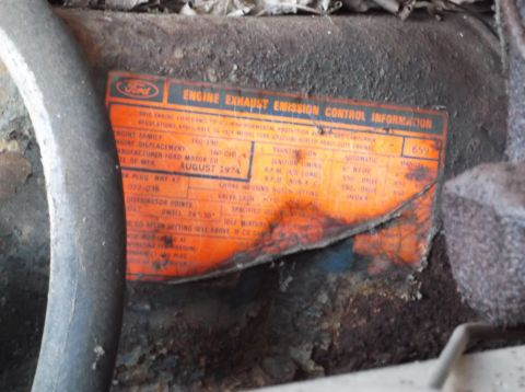 1974 Dodge Challenger - An orange Ford emission control sticker with manufacturing date August 1974 is attached to an engine component.