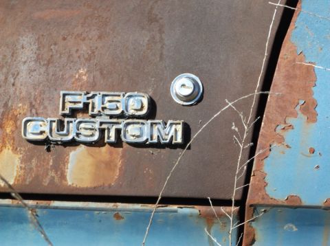 1974 Dodge Challenger - Close-up of the F150 CUSTOM badging on a heavily rusted blue vehicle.