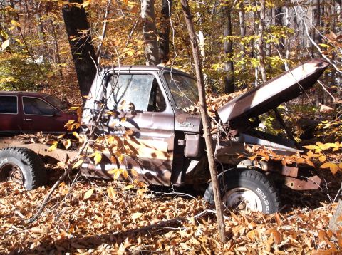 1974 Dodge Challenger - Two vehicles sit abandoned in a wooded area during autumn, covered in fallen leaves.