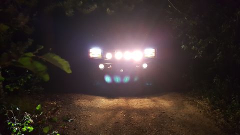 1996 Ford Bronco - Front view of a 1996 Ford Bronco at night, illuminated by its headlights and auxiliary lights.