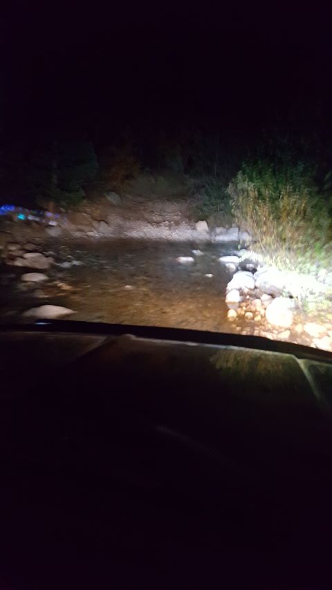 1996 Ford Bronco - Driving through a rocky stream at night, illuminated by headlights, from the perspective of the vehicle's interior.