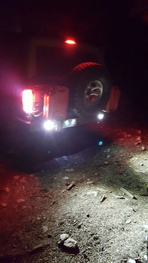 1996 Ford Bronco - The rear of a 1996 Ford Bronco is visible at night, with its taillights and external spare tire illuminated.