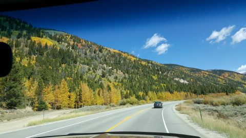 1996 Ford Bronco - Road trip through mountains during autumn, with a single car ahead.