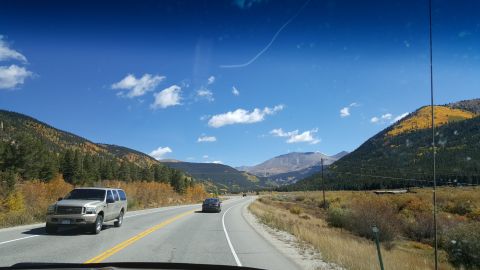 1996 Ford Bronco - SUV driving on a highway surrounded by mountains and fall colors.