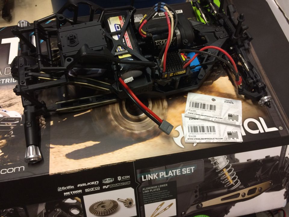 RC car chassis with battery, motor, and wiring. Two small packages of parts sit on top of a box