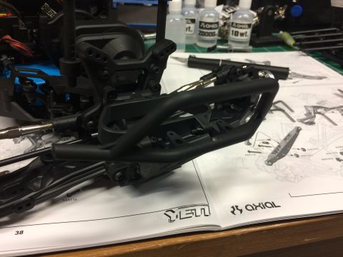 1989 Ford Bronco - Assembly instructions for an RC car chassis are spread out with parts and tools nearby.