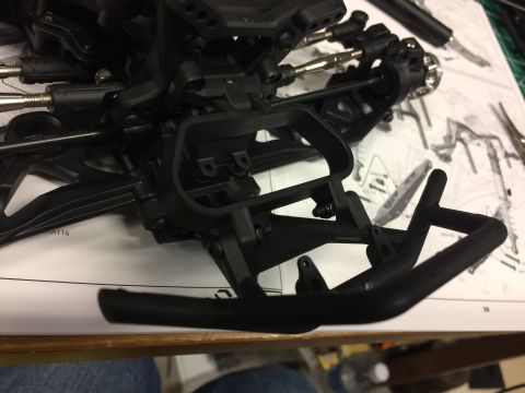 1989 Ford Bronco - Close-up of a black plastic RC car chassis part, showing suspension and bumper details on an instruction manual.