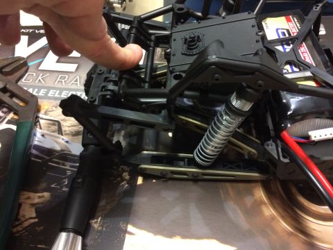 1989 Ford Bronco - A hand adjusts the chassis of a remote control car, revealing its internal components and wiring.